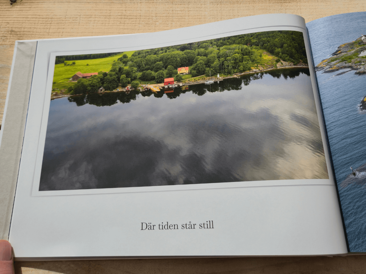 Sida ur fotobok med bild på några hus som står på en strandkant
